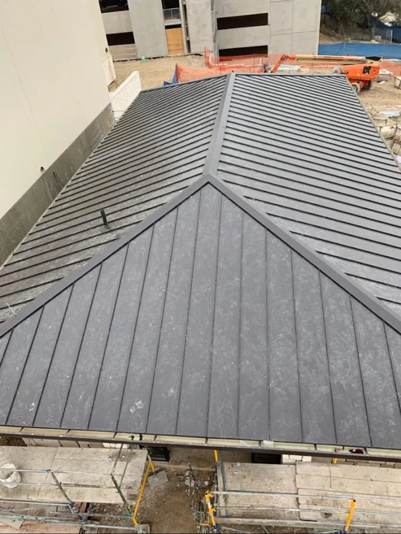 Commercial metal roof construction with crane equipment in Mason